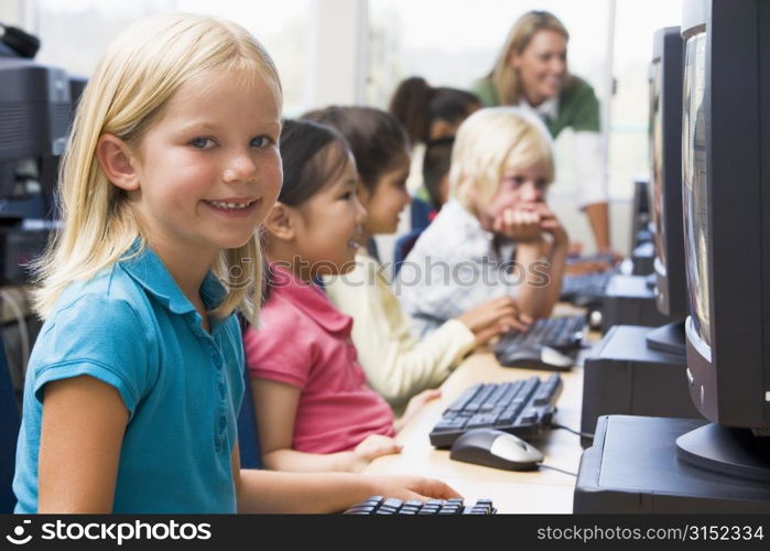 Children at computer terminals with teacher in background (depth of field/high key)