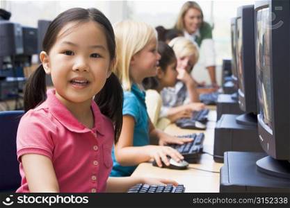 Children at computer terminals with teacher in background (depth of field/high key)