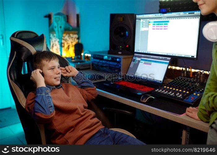 Children at recording studio preteen boy listening new soundtrack sitting at desk table with sound production equipment. Children at recording studio boy listening new soundtrack