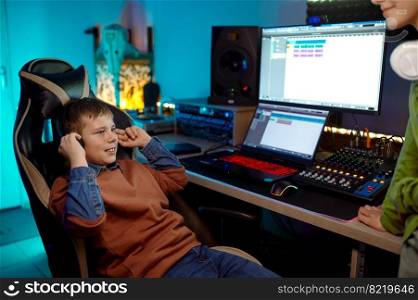 Children at recording studio preteen boy listening new soundtrack sitting at desk table with sound production equipment. Children at recording studio boy listening new soundtrack