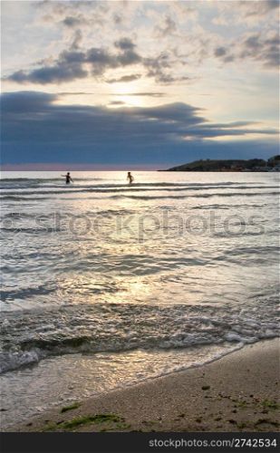 Children bathe and play in evening sea