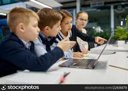 Children brainstorming looking at laptop screen discussing something. Schoolkids business IT group. Children looking at laptop screen discussing something