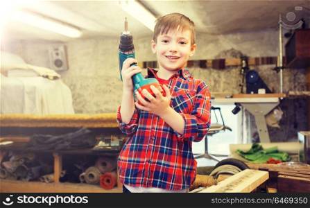 children, carpentry, profession and people concept - happy little boy with drill at workshop. happy little boy with drill at workshop