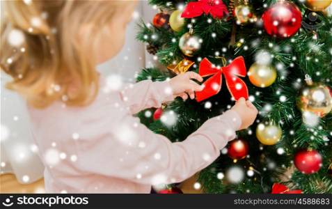 children, christmas, new year, holidays and people concept - close up of little girl decorating christmas tree at home