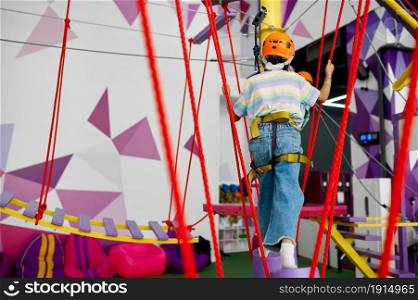 Children climb on zip line in entertainment center, little climbers. Boy and girl having fun on ropes in climbing area, kids spend the weekend on playground, happy childhood. Children climb on zip line, little climbers