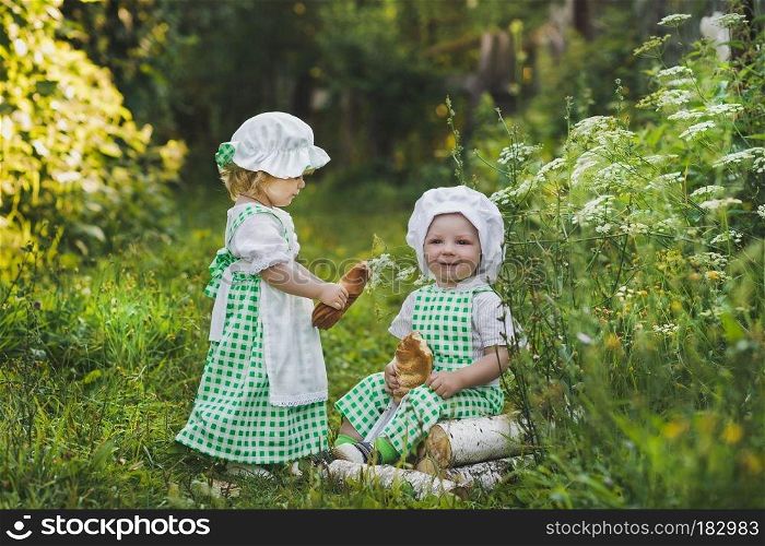 Children clothing bakers walking in the garden.. Little children in clothes bakers with loaves 4682.