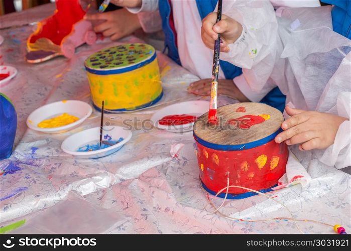 Children decorating handmade drum. Young children decorating handmade drum
