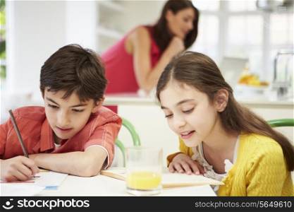 Children Doing Homework As Mother uses Laptop In Background