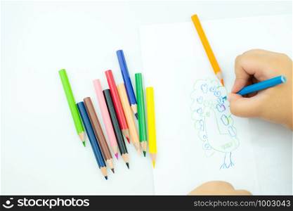 Children draw paints in the playroom, A child is holding a crayon in his hands at paper and crayons for drawing on the table, Hand Kids drawings, children's creativity