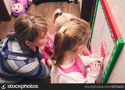 Children drawing a pictures learning a letters playing together using whiteboard and markers