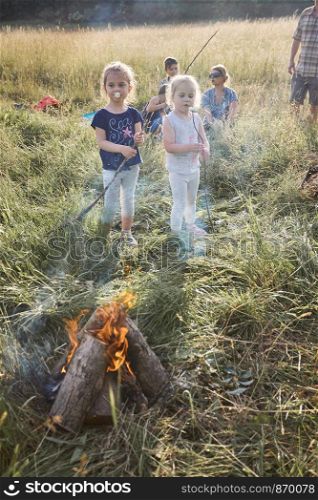 Children eating a marshmallows after roasting them over a campfire on a meadow. Candid people, real moments, authentic situations