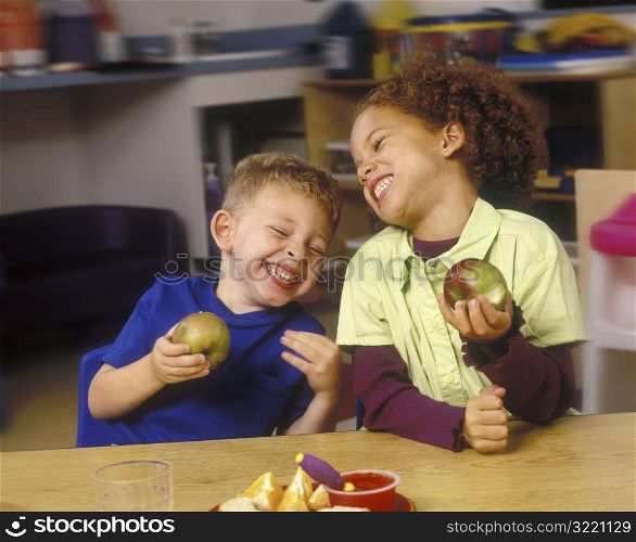 Children Eating Apples And Laughing In Classroom