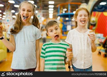 Children eats ice cream in the entertainment center. Boy and girls leisures on holidays, childhood happiness, happy kids on playground. Children eats ice cream in entertainment center