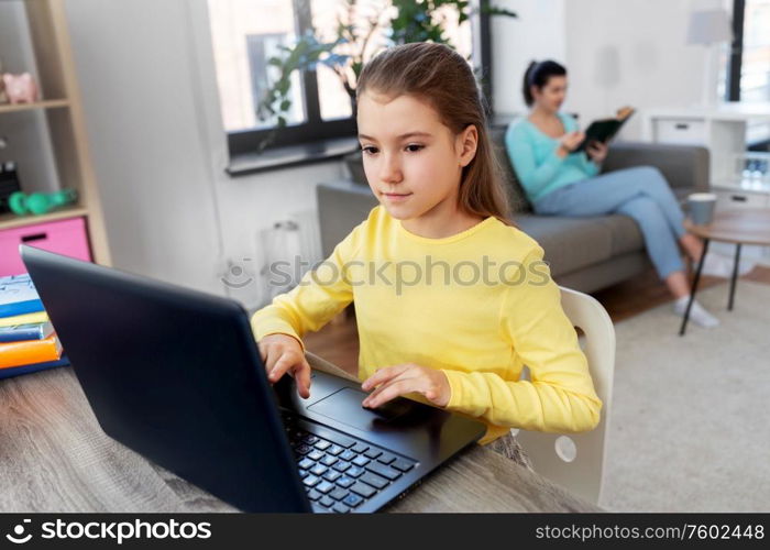 children, education and distant learning concept - student girl with laptop computer and mother reading book at home. student girl with laptop learning online at home