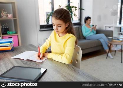 children, education and distant learning concept - student girl with tablet pc computer writing to notebook and mother with smartphone at home. student girl with tablet pc learning at home