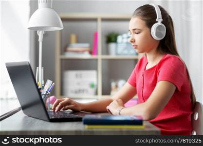 children, education and distant learning concept - teenage student girl in headphones with laptop computer at home. girl in headphones with laptop computer at home