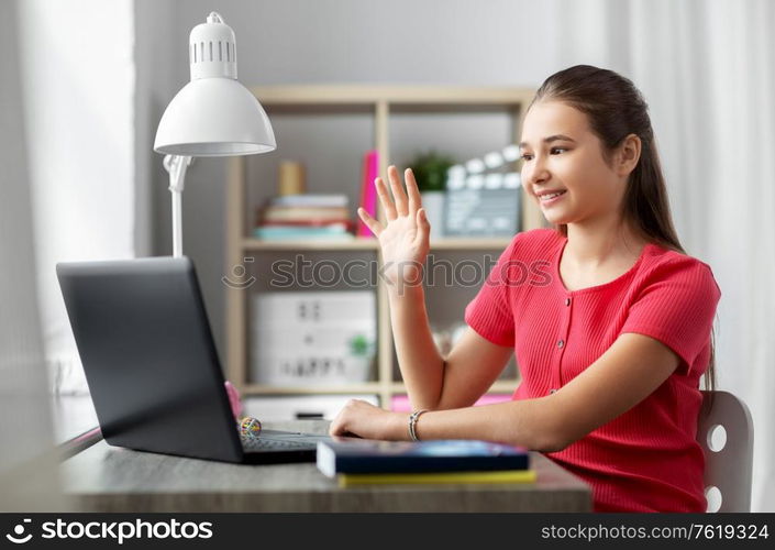 children, education and e-learning concept - happy smiling teenage student girl with laptop computer having video call at home. student girl with laptop having video call at home