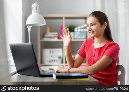 children, education and e-learning concept - happy smiling teenage student girl with laptop computer having video call at home. student girl with laptop having video call at home