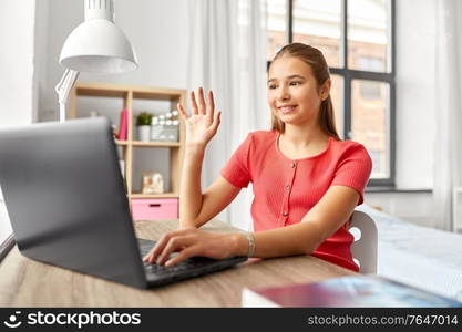 children, education and e-learning concept - happy smiling teenage student girl with laptop computer having video call at home. student girl with laptop having video call at home