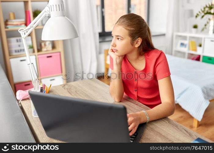 children, education and learning concept - bored teenage student girl with laptop computer at home. student girl with laptop computer learning at home