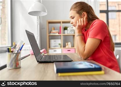 children, education and learning concept - bored teenage student girl with laptop computer at home. student girl with laptop computer learning at home