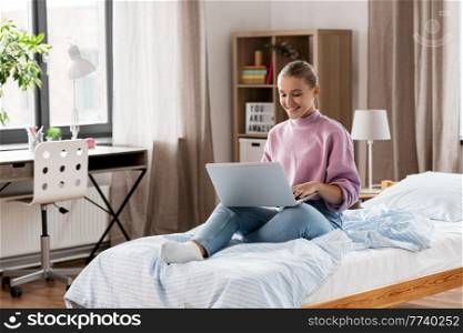 children, education and learning concept - happy smiling student girl with laptop computer at home. student girl with laptop computer learning at home