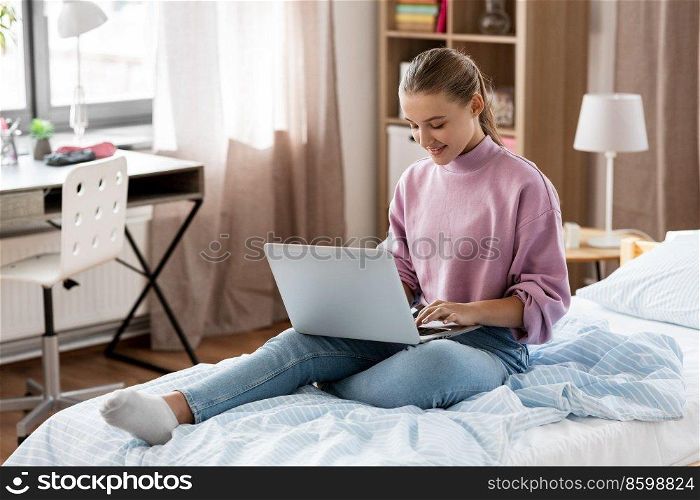children, education and learning concept - happy smiling student girl with laptop computer at home. student girl with laptop computer learning at home