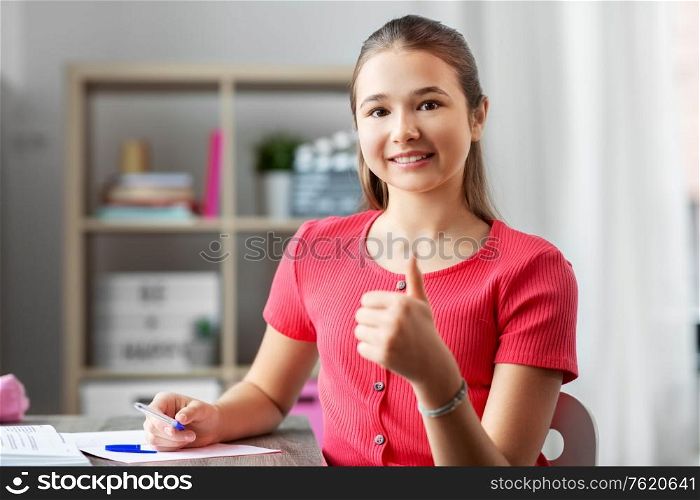 children, education and learning concept - happy smiling teenage student girl with books showing thumbs up at home. teenage student gir showing thumbs up at home