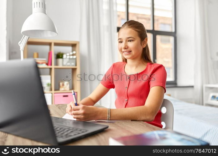 children, education and learning concept - happy smiling teenage student girl with laptop computer at home. student girl with laptop computer learning at home