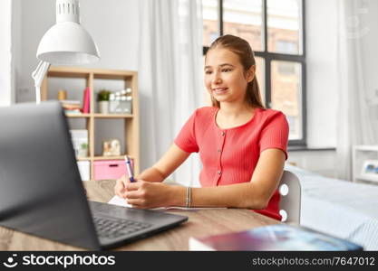 children, education and learning concept - happy smiling teenage student girl with laptop computer at home. student girl with laptop computer learning at home