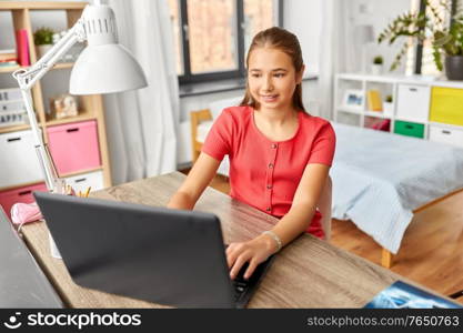 children, education and learning concept - happy smiling teenage student girl with laptop computer at home. student girl with laptop computer learning at home