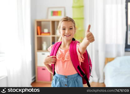 children, education and learning concept - happy student girl with school bag showing thumbs up at home. student girl with school bag showing thumbs up