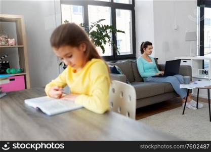 children, education and learning concept - mother with laptop computer and papers working at home office and daughter studying. mother working and daughter studying at home