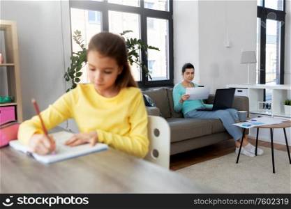 children, education and learning concept - mother with papers and laptop computer working at home office and daughter studying. mother working and daughter studying at home
