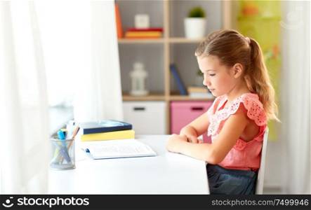 children, education and learning concept - sad student girl with book at home. sad student girl with book at home