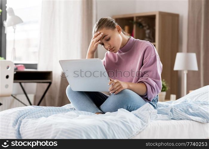 children, education and learning concept - sad student girl with laptop computer at home. student girl with laptop computer learning at home
