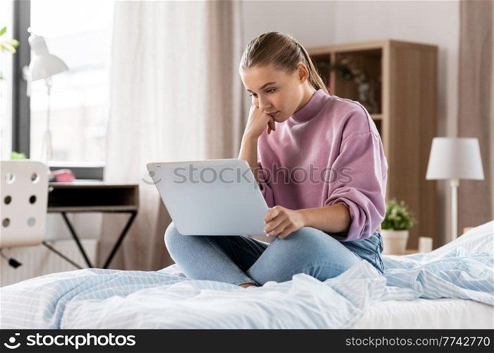 children, education and learning concept - sad student girl with laptop computer at home. student girl with laptop computer learning at home