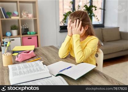 children, education and learning concept - stressed little student girl with book and notebook at home. stressed little student girl learning at home