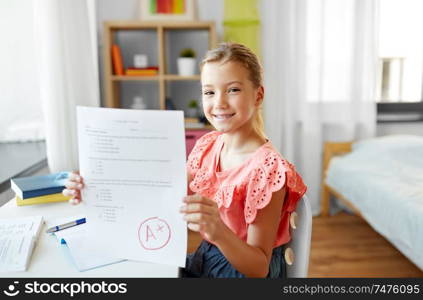 children, education and learning concept - student girl with good mark on school test at home. student girl with school test good mark at home