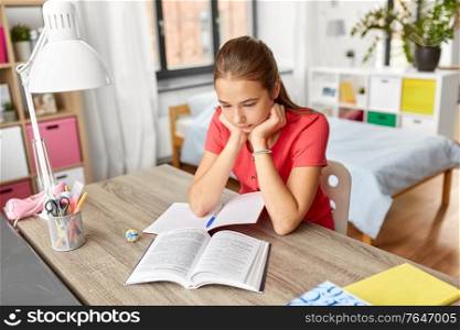 children, education and learning concept - student teenage girl reading book at home. student teenage girl reading book at home