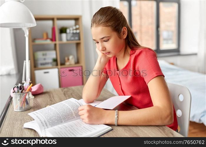 children, education and learning concept - student teenage girl reading book at home. student teenage girl reading book at home