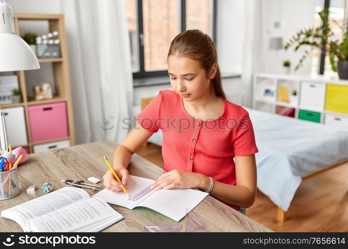 children, education and learning concept - student teenage girl with ruler drawing line in notebook at home. student girl with ruler drawing line in notebook