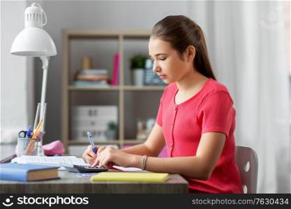 children, education and learning concept - teenage student girl counting on calculator at home. student girl counting on calculator at home