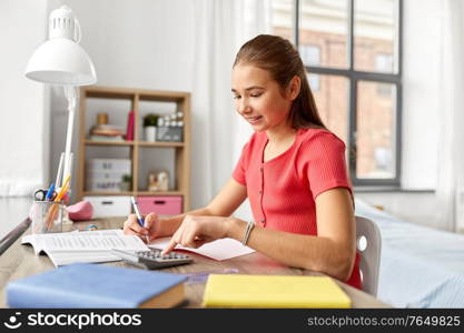 children, education and learning concept - teenage student girl counting on calculator at home. student girl counting on calculator at home