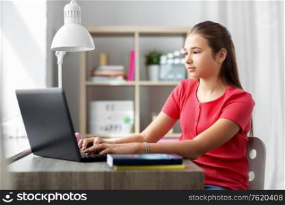 children, education and learning concept - teenage student girl with laptop computer at home. student girl with laptop computer learning at home
