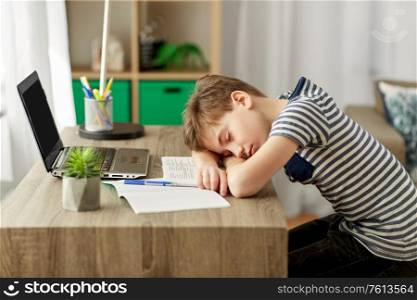 children, education and learning concept - tired student boy sleeping on desk at home. tired student boy sleeping on desk at home
