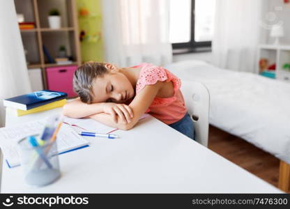 children, education and learning concept - tired student girl sleeping on table at home. tired student girl sleeping on table at home
