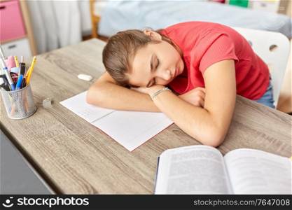children, education and learning concept - tired teenage student girl sleeping on table at home. tired student girl sleeping on table at home