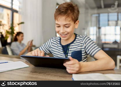 children, education and school concept - happy student boy with tablet pc computer learning at home. student boy with tablet computer learning at home