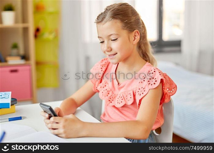 children, education and technology concept - happy student girl using smartphone at home. happy student girl using smartphone at home